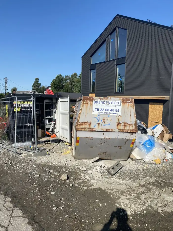 Svart hus under bygging med container foran
