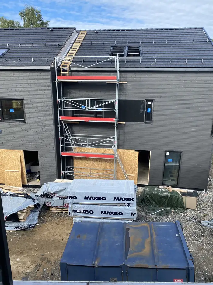 Grått hus med stillas og byggevarer foran