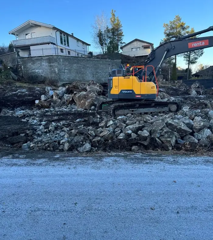 Gravemaskin rydder stein på tomten