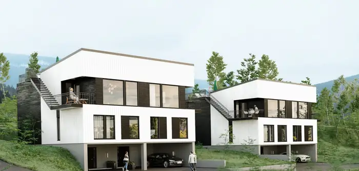 To hvite hus med svart sokkel i en skråning