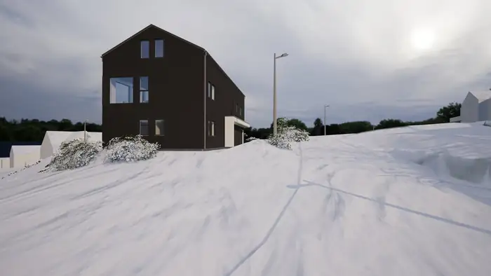 Svart hus med saltak sett fra gavlen, i snø