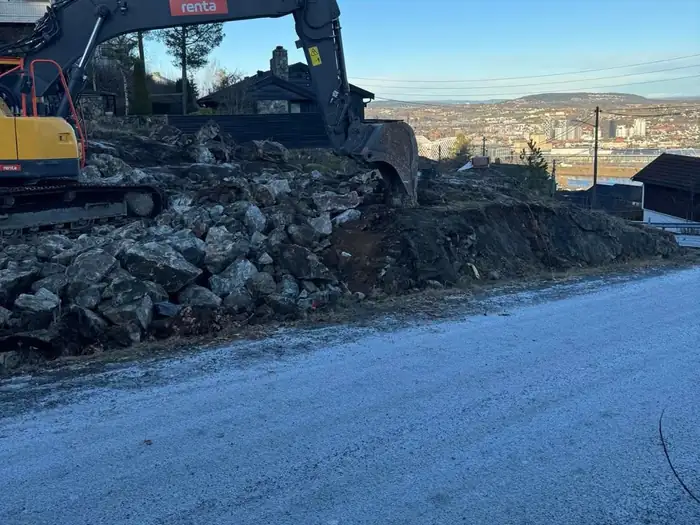 Gravemaskin på en byggetomt med utsikt over byen