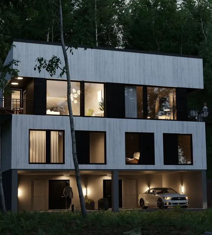 Hvit og svart bolig i tre plan om kvelden, med lys i vinduene og carport under