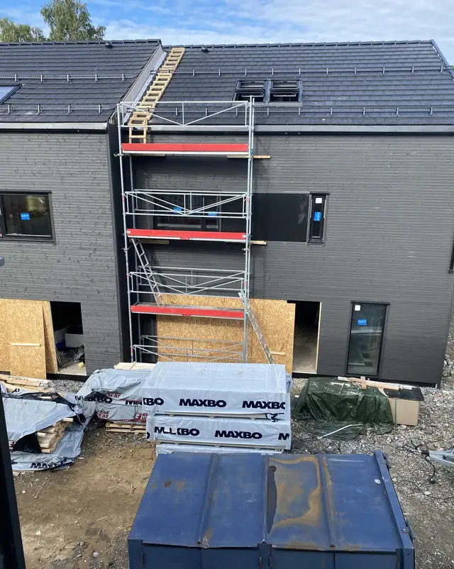 Hus med stillas og byggevarer foran